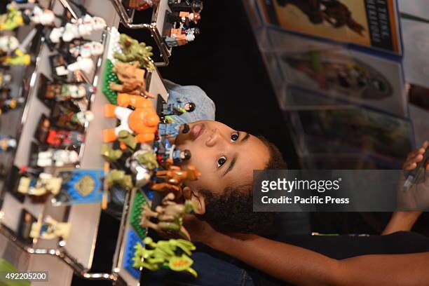 Little boy inspects tiny plastic models. Hundreds of thousands of fans, artists, entrepreneurs and folks who were simply curious descended on Javits...