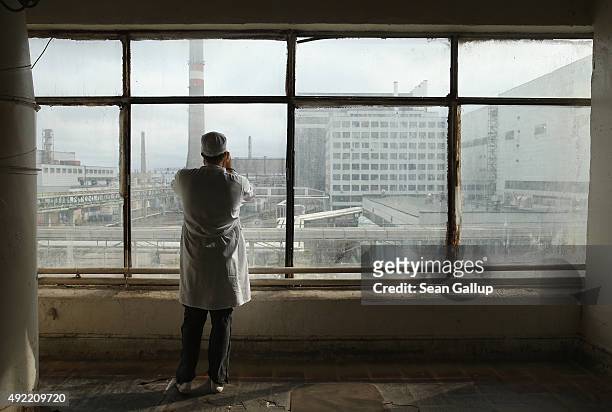 Visitor touring the former Chernobyl nuclear power plant takes a photo through a window looking towards facilities that house reactors one and two on...