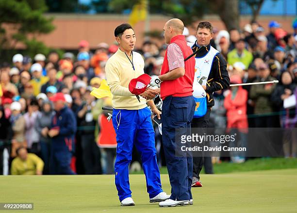 Bill Haas of the United States team shakes hands with Sangmoon Bae of South Korea and the International team after Haas won the final match on the...