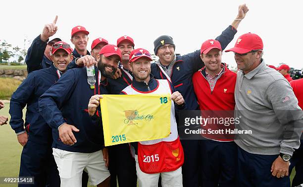 Caddie John Wood of The United States Team poses with fellow caddies on the 18th green after their 15.5-14.5 win over the International Team during...