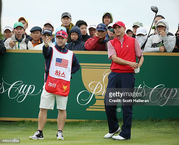 Bill Haas of the United States Team lines up his tee shot on the 18th hole with his caddie John Wood during the Sunday singles matches at The...