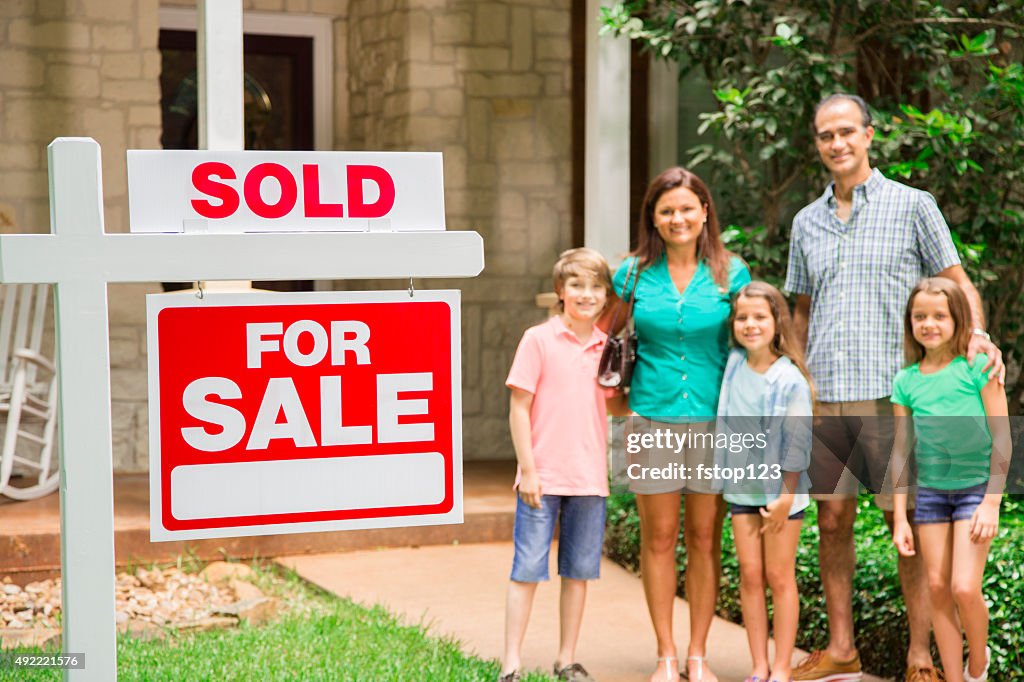 Family with "house for sale, sold" real estate sign. Summer.
