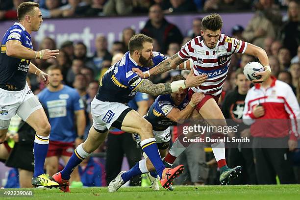 Oliver Gildart of Wigan Warriors is tackled by Rob Burrow and Adam Cuthertson of Leeds Rhinos during the First Utility Super League Grand Final...