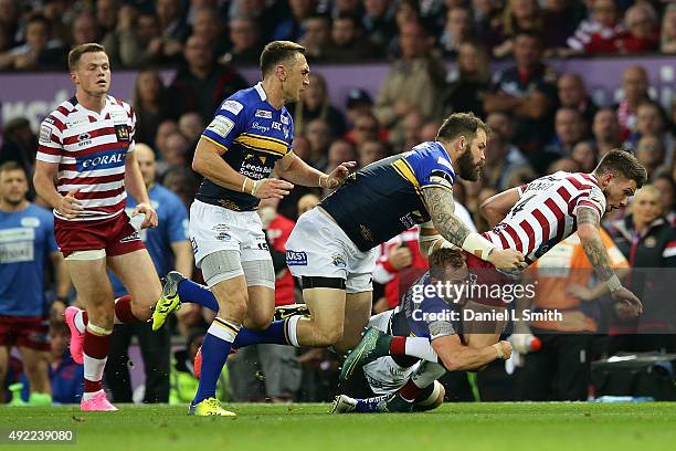 Oliver Gildart of Wigan Warriors is taken down in a tackle by Rob Burrow of Leeds Rhinos during the First Utility Super League Grand Final between...