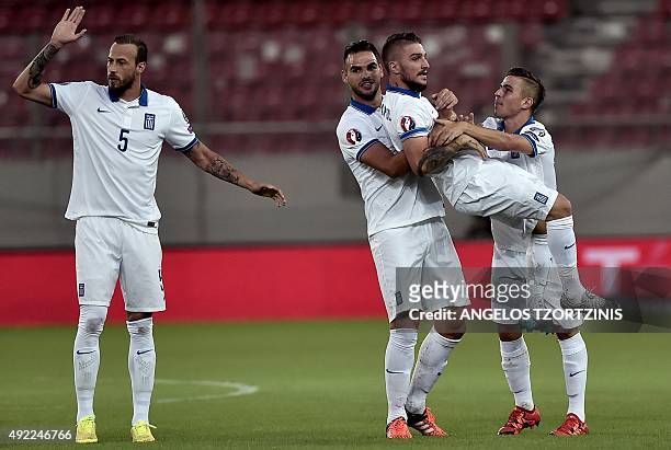 Greece's Kostas Stafylidis is lifted by teammate after he scored during the UEFA Euro 2016 qualifying Group F football match between Greece and...