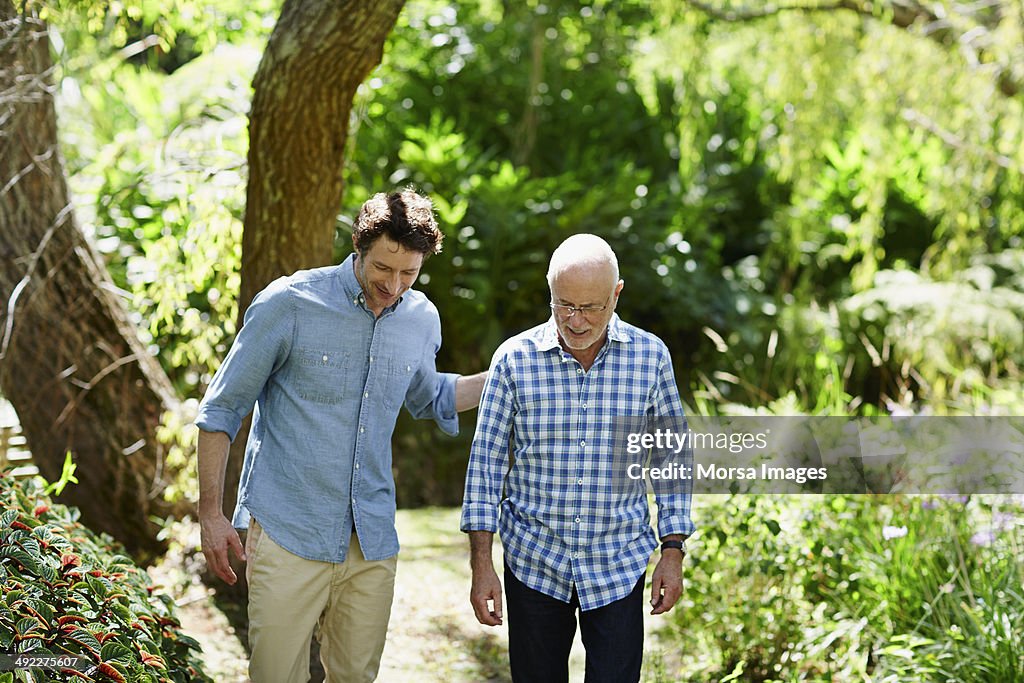 Senior man and son walking in park