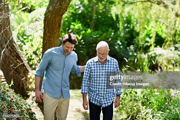 senior man and son walking in park - two people talking outside stock pictures, royalty-free photos & images