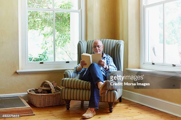 senior man reading book at home - reading stock-fotos und bilder