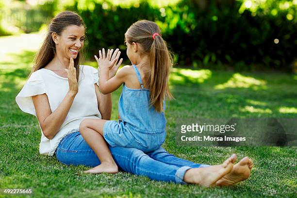 mother and daughter playing pattycake in park - clapping game stock pictures, royalty-free photos & images