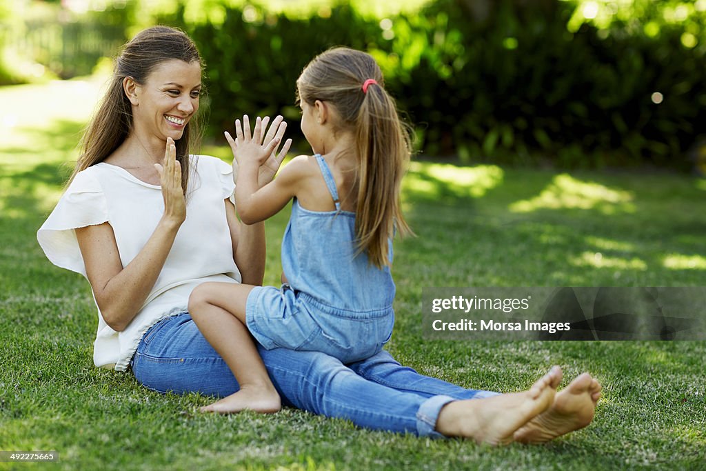 Mother and daughter playing pattycake in park