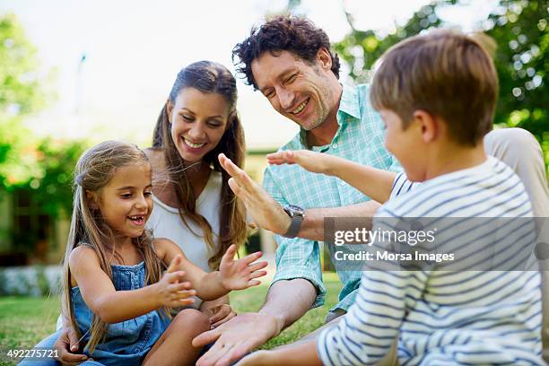 family playing pat-a-cake in lawn - clapping game stock pictures, royalty-free photos & images