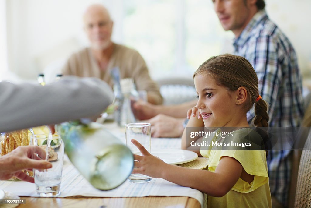 Girl looking at mother pouring water in glass