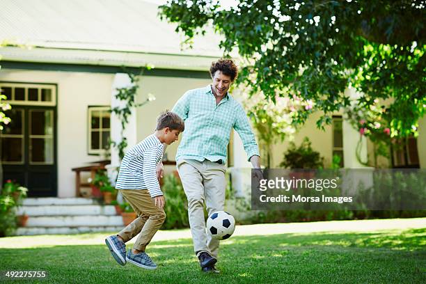 father and son playing soccer in lawn - calciare foto e immagini stock
