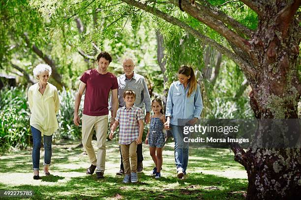 family walking together in park - family walking stock pictures, royalty-free photos & images