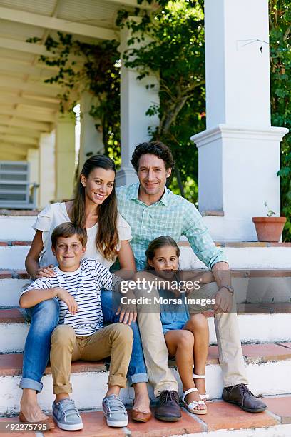 happy parents with children sitting on steps outsi - family porch foto e immagini stock