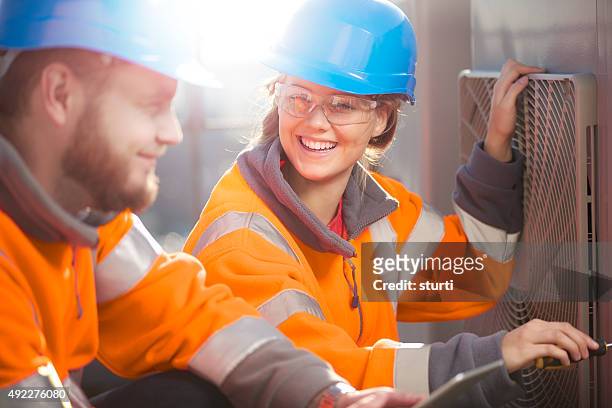 female air conditioning technician with her supervisor - young adult stockfoto's en -beelden