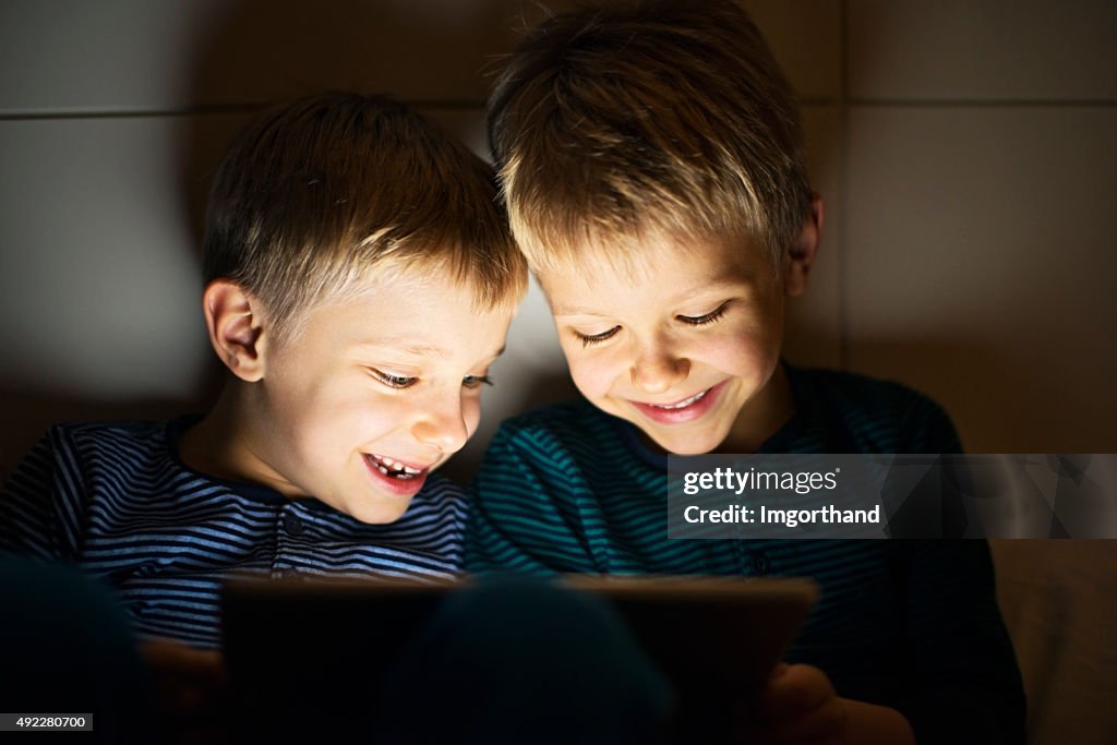 Kids secretly playing with digital tablet at night