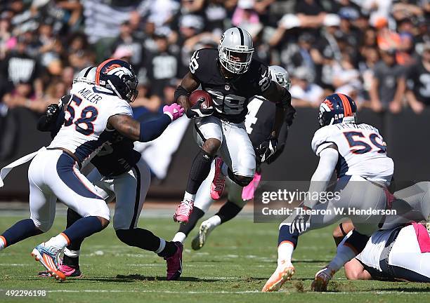 David Amerson of the Oakland Raiders jumps through the Denver Broncos defense in the first quarter at O.co Coliseum on October 11, 2015 in Oakland,...