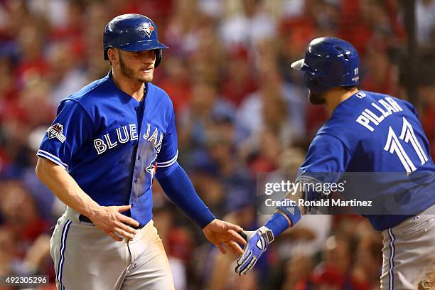 Josh Donaldson of the Toronto Blue Jays celebrates with Kevin Pillar after scoring a run off of Troy Tulowitzki being walked by Martin Perez of the...