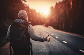 Hitchhiking traveler trying to stop the car on road