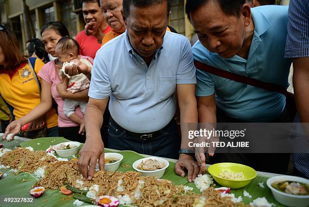 Philippine vice-President Jejomar Binay eats in a "boodle fight" with residents and supporters near an informal settlers area before filing his...