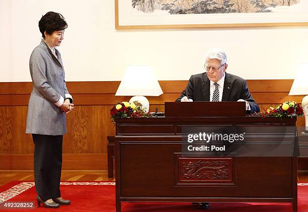 German President Joachim Gauck signs his name in the visitors' book as South Korean President Park Geun-Hye looks at the presidential house on...