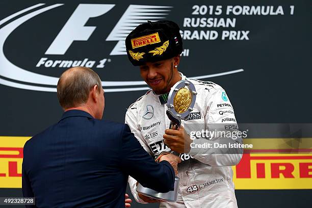 Lewis Hamilton of Great Britain and Mercedes GP is presented with the trophy by President of Russia, Vladimir Putin after winning the Formula One...