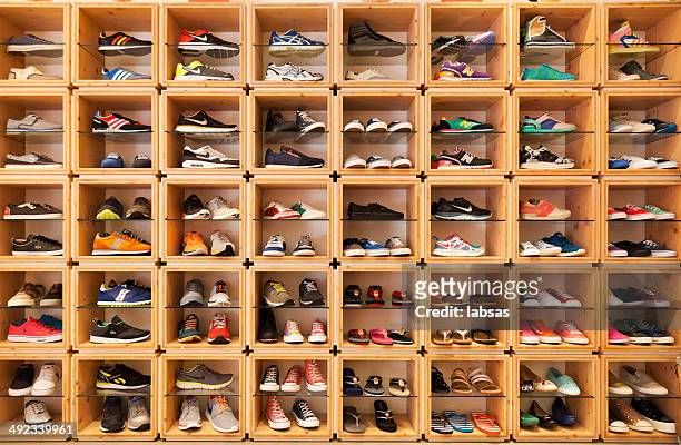 different shoes displayed in a shoe shop. - sportschoen stockfoto's en -beelden