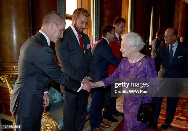 Queen Elizabeth II shakes hands with England Rugby Union head coach Stuart Lancaster as England captain Chris Robshaw looks on, during a reception to...