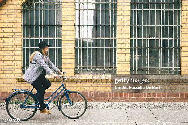 trendy young woman with her bike, urban landscape on background - first sunny spring day in berlin stock pictures, royalty-free photos & images