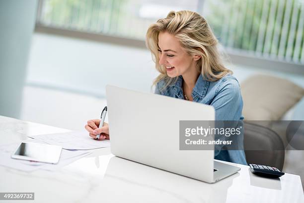 woman paying her bills online on a laptop - college for creative studies stock pictures, royalty-free photos & images