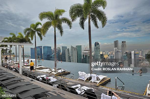 Visitors look at a view of the city skyline from the rooftop pool of the Marina Bay Sands resort hotel in Singapore on May 20, 2014. Singapore's...