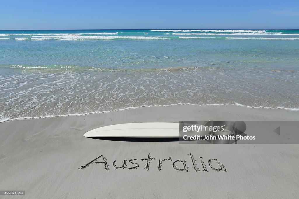 Australia written on a beach with a surfboard