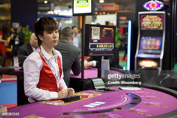 Croupier stands at a poker table at the Bally Technologies Inc. Booth at the Global Gaming Expo inside the Venetian Macao resort and casino, operated...