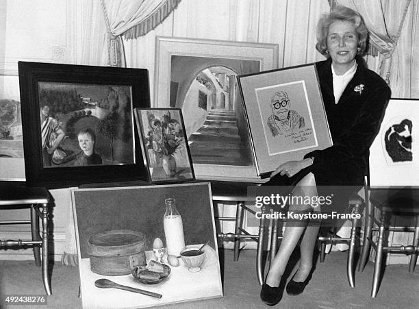 Alix de Rothschild entouree de peintures realisees par des celebrites a l'occasion d'un gala de charite pour l'enfance le 6 janvier, 1968.