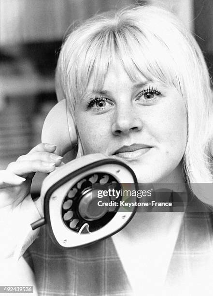 Une jeune femme presente un nouveau genre de telephone, invention suedoise, dont le cadran se situe sous le pied de l'appareil le 25 aout, 1964 a...