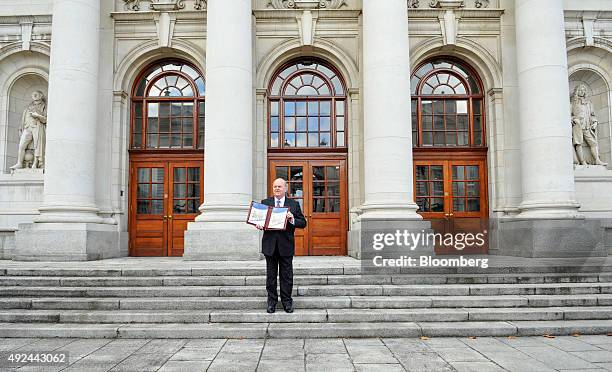 Michael Noonan, Ireland's finance minister, poses for photographs holding the Irish budget document on the steps of the government buildings in...