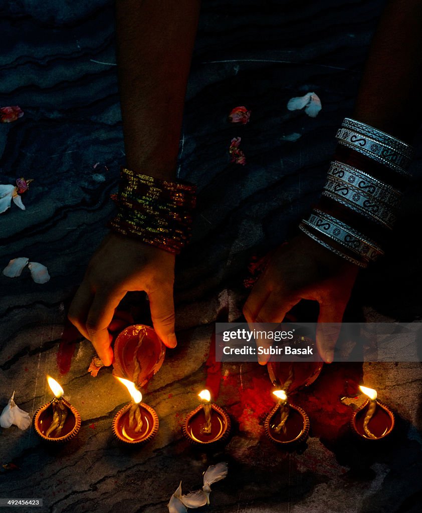 Women lighting up earthen lamps