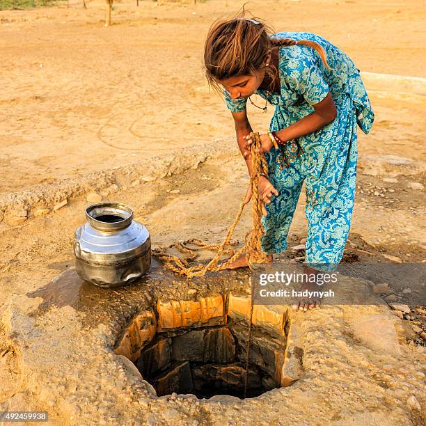 indischer junge mädchen zeichnen wasser aus einem gut, rajasthan - rajasthani youth stock-fotos und bilder