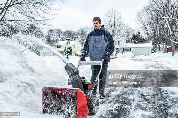 young snowblower guy clearing snow from suburban driveway - snow blower stock pictures, royalty-free photos & images