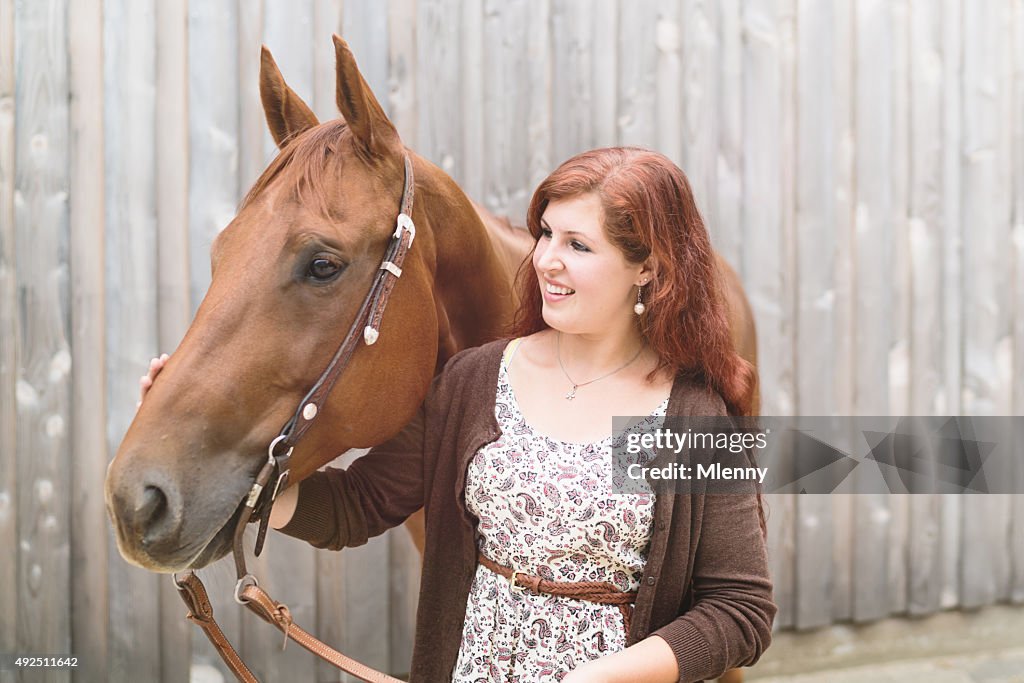 Happy young woman together with her brown horse
