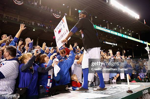 Dexter Fowler of the Chicago Cubs celebrates with fans after defeating the St. Louis Cardinals in game four of the National League Division Series to...