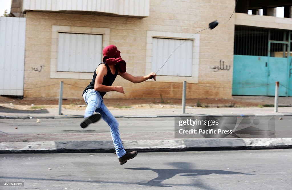 A masked Palestinian demonstrator hurls a rock towards the...