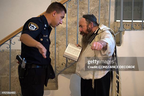 An Israeli police man askes a Jewish man reciting the Psalm of David to leave the Cenacle or Upper Room on Mount Zion just outside the Old City of...