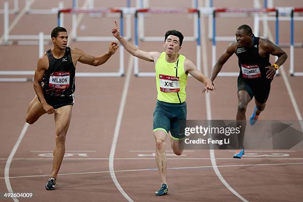 Chinese hurdler Xie Wenjun crosses the finishing line as Ryan Wilson and Ray Stewart of United States followed during the Men's 110-meter hurdles of...