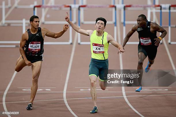Chinese hurdler Xie Wenjun crosses the finishing line as Ryan Wilson and Ray Stewart of United States followed during the Men's 110-meter hurdles of...