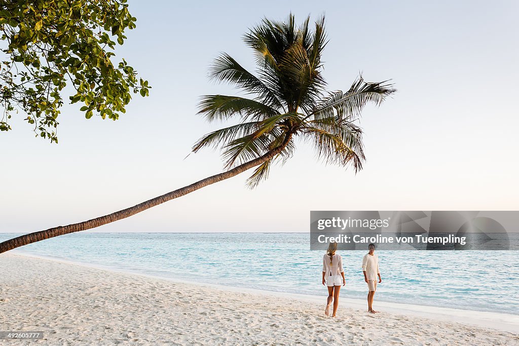 Young couple walking on beach at sunset