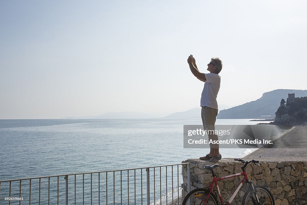 Man takes pic with smart phone above sea, beach
