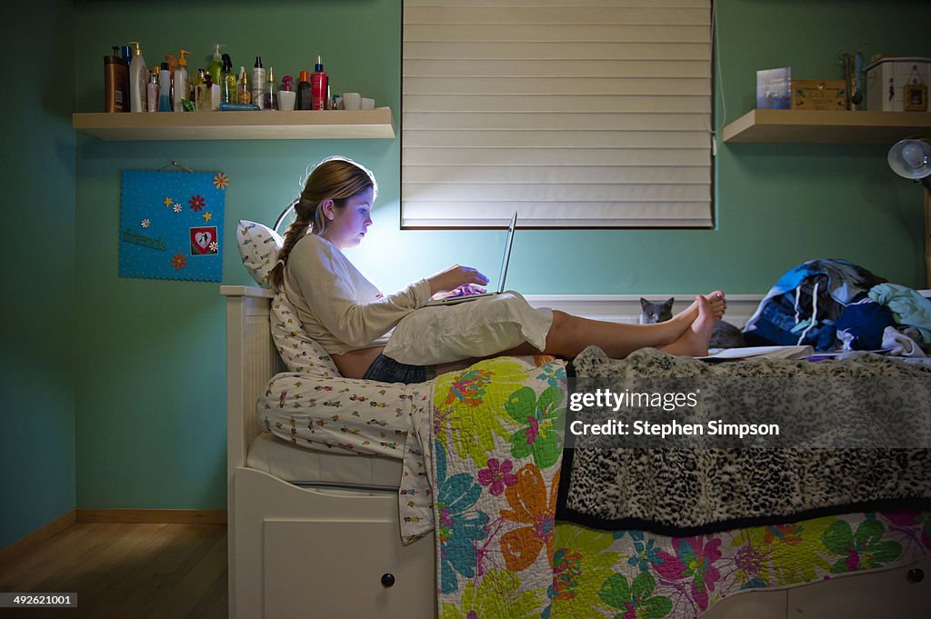 Teen girl on laptop in her bedroom
