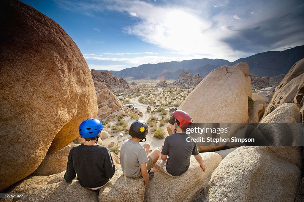 Three boys explore boulders at sunrise